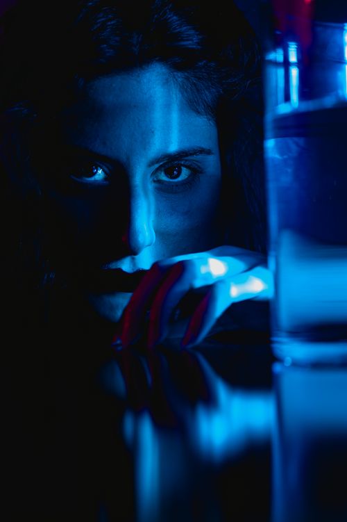 Free Artistic portrait of a woman in blue light with reflections on a black background. Stock Photo