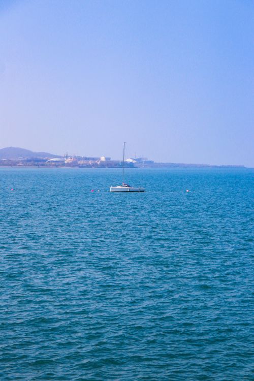 Free A serene sailboat floats on the calm ocean, capturing the essence of a peaceful summer day. Stock Photo