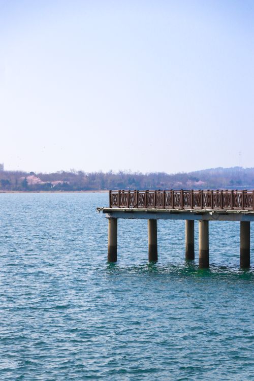 Free Tranquil scene of a wooden pier extending over a blue lake under a clear sky. Stock Photo