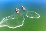 航拍下，渔民在充满活力的绿色水面上撒网