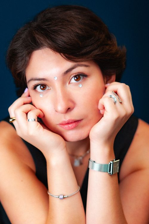 Free Close-up portrait of a brunette woman with jewelry, posing thoughtfully with hands on cheeks. Stock Photo