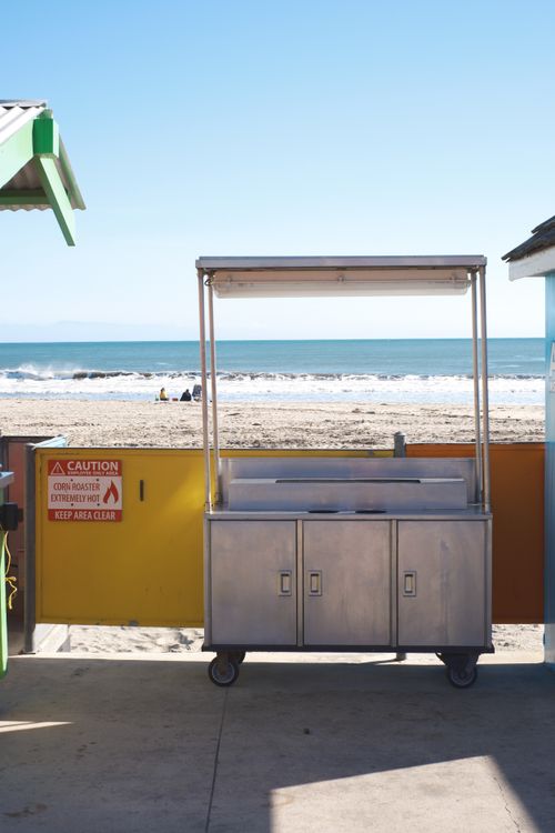 Free Empty food cart by the beach with a clear ocean view, perfect for seaside businesses. Stock Photo