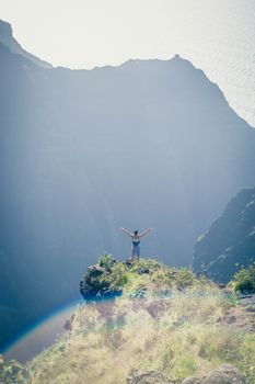 一个人站在山峰上，周围是大自然