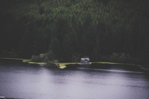 Free A solitary house by a serene lake surrounded by dense forest, depicting tranquility. Stock Photo