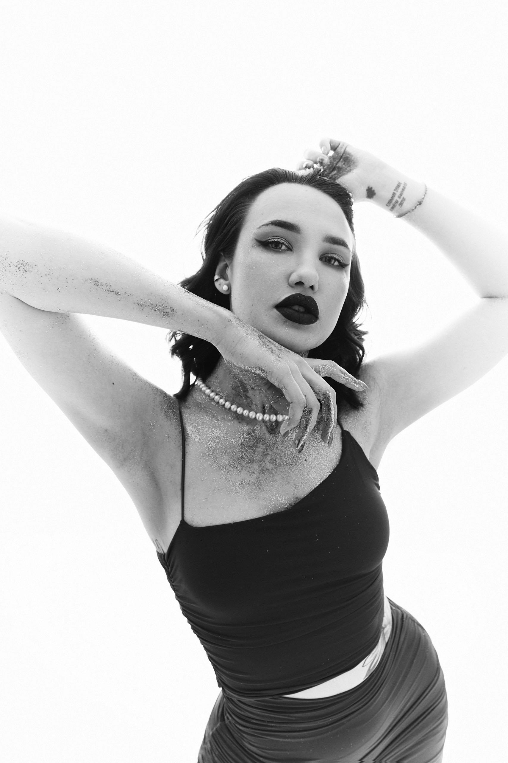 A striking black and white portrait of a woman in glitter makeup posing gracefully, exuding elegance and style.