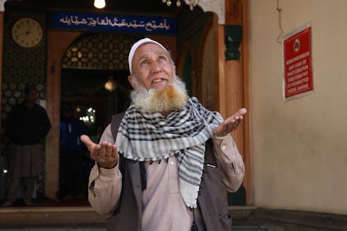 A man in a white scarf and a turban is praying