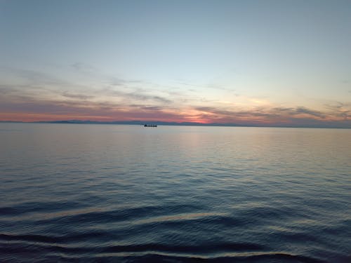 calm sea during sunset with ship in background 