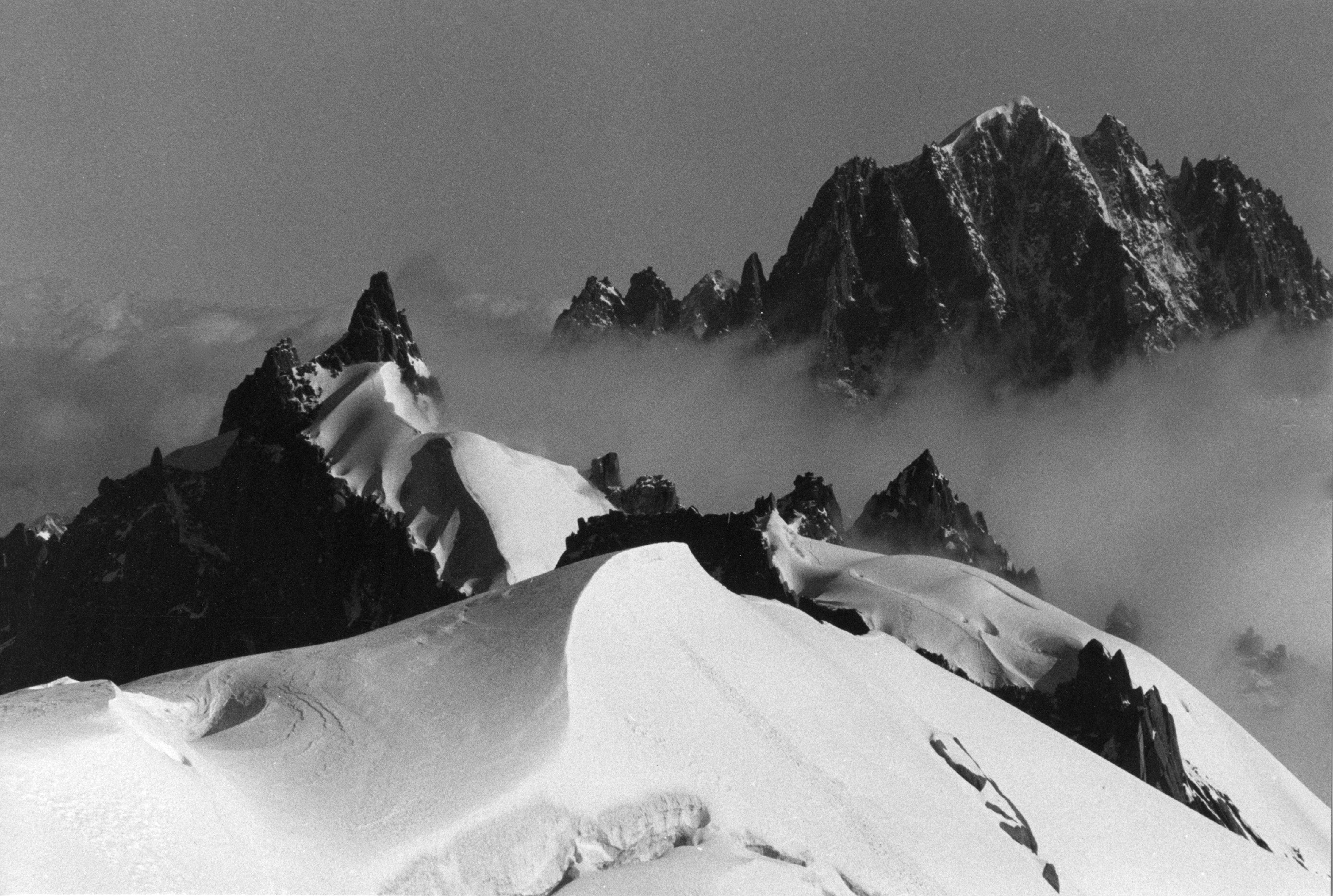 Dramatic black and white image of foggy mountain peaks and snow-covered ridges.