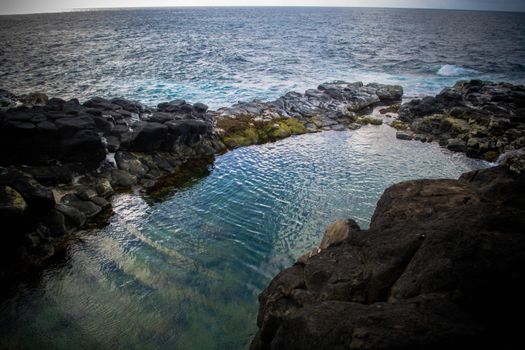 A serene tide pool surrounded by jagged rocks overlooking a vast ocean at dusk.. pexels, serene, tide