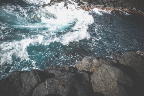 Free A powerful ocean wave crashes against rugged coastal rocks, creating a dramatic seascape. Stock Photo