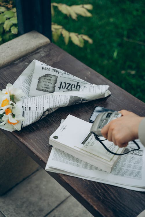 Free A person is holding a camera and flowers on a bench Stock Photo