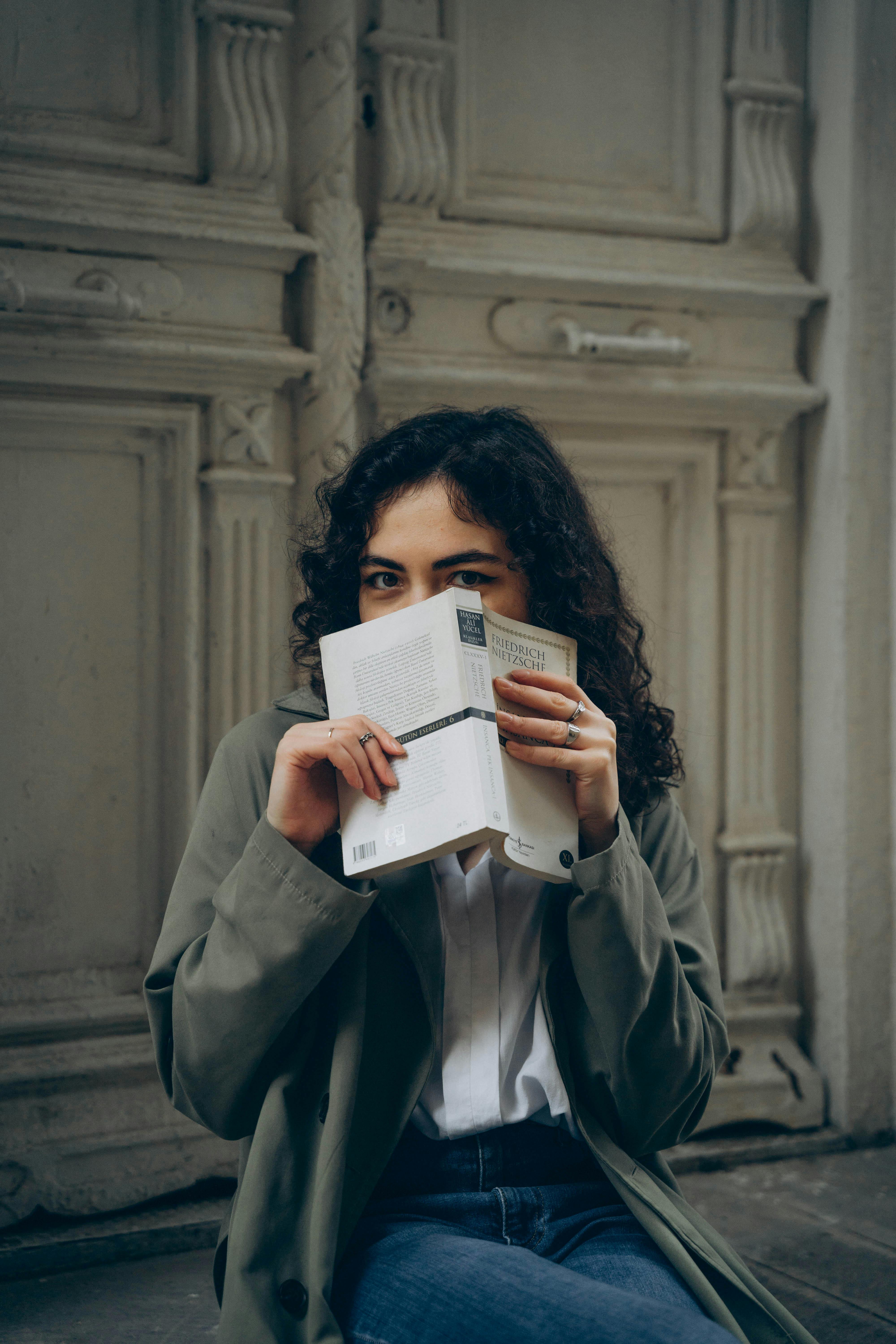 Young woman with a book, seated near historic doors in Baku.