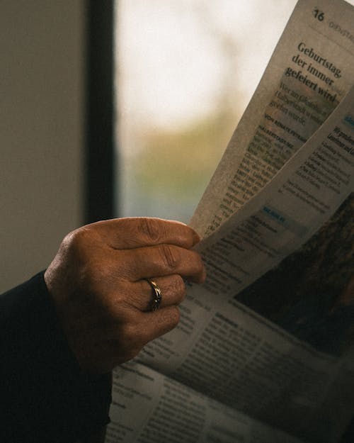 A person holding a newspaper in their hand