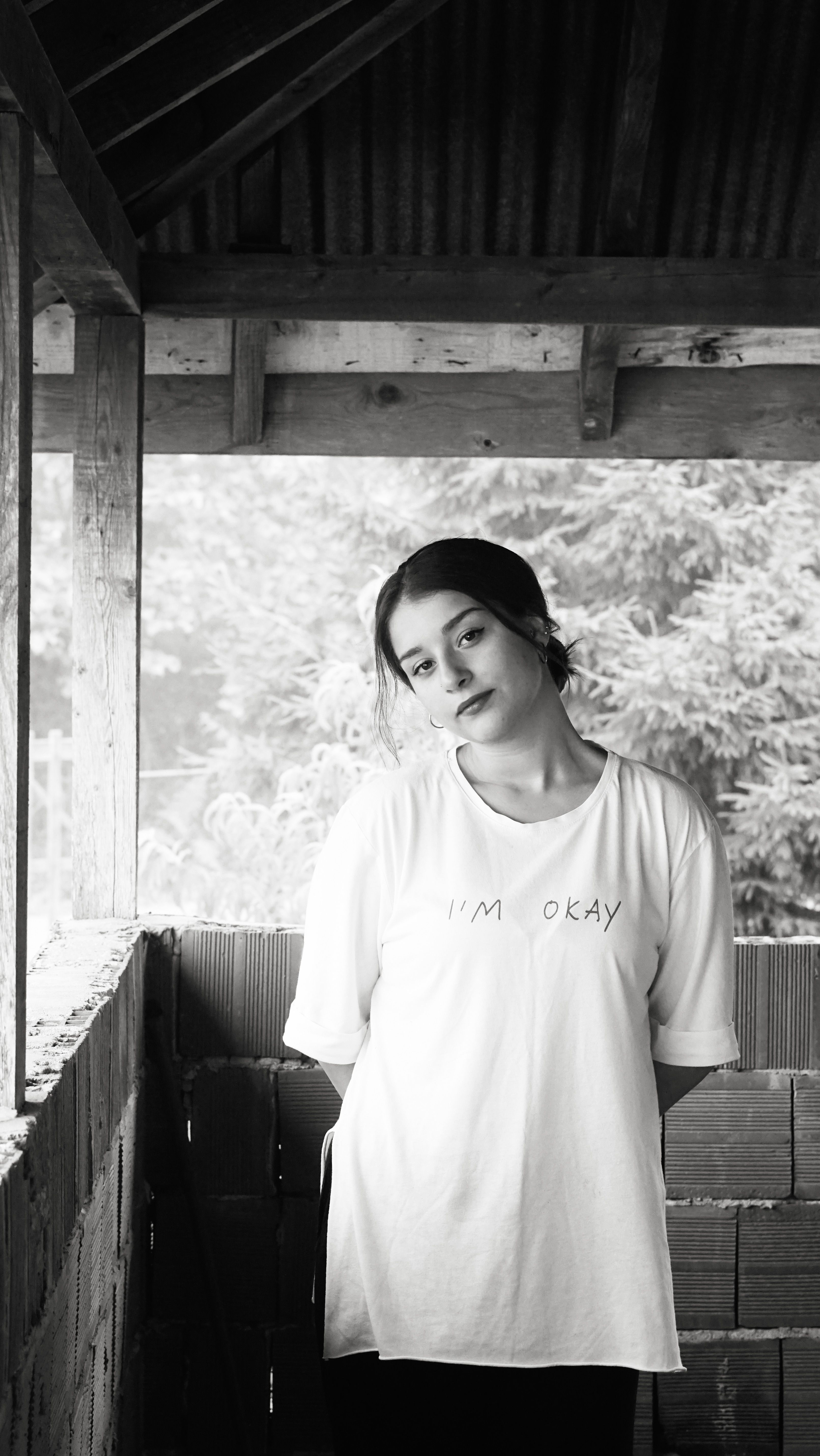 Portrait of a young woman posing in a monochrome gazebo, casual fashion, serene setting.