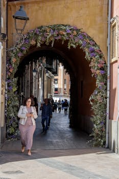 A vibrant floral archway decorates a historic passage in Murcia, Spain.