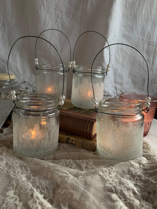 Four glass jars with candles and wire hanging from them