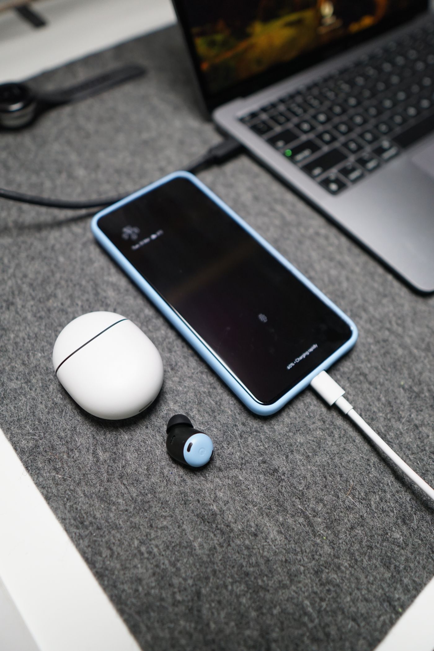 Smartphone and wireless earphones arranged beside a laptop