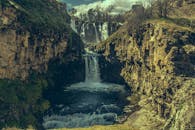 瀑布从岩石峡谷中倾泻而下，四周环绕着郁郁葱葱的绿色植物，头顶是蓝天，令人惊叹