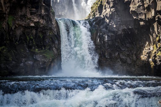瀑布从崎岖的岩石上倾泻而下，四周环绕着郁郁葱葱的绿色植物，景色迷人