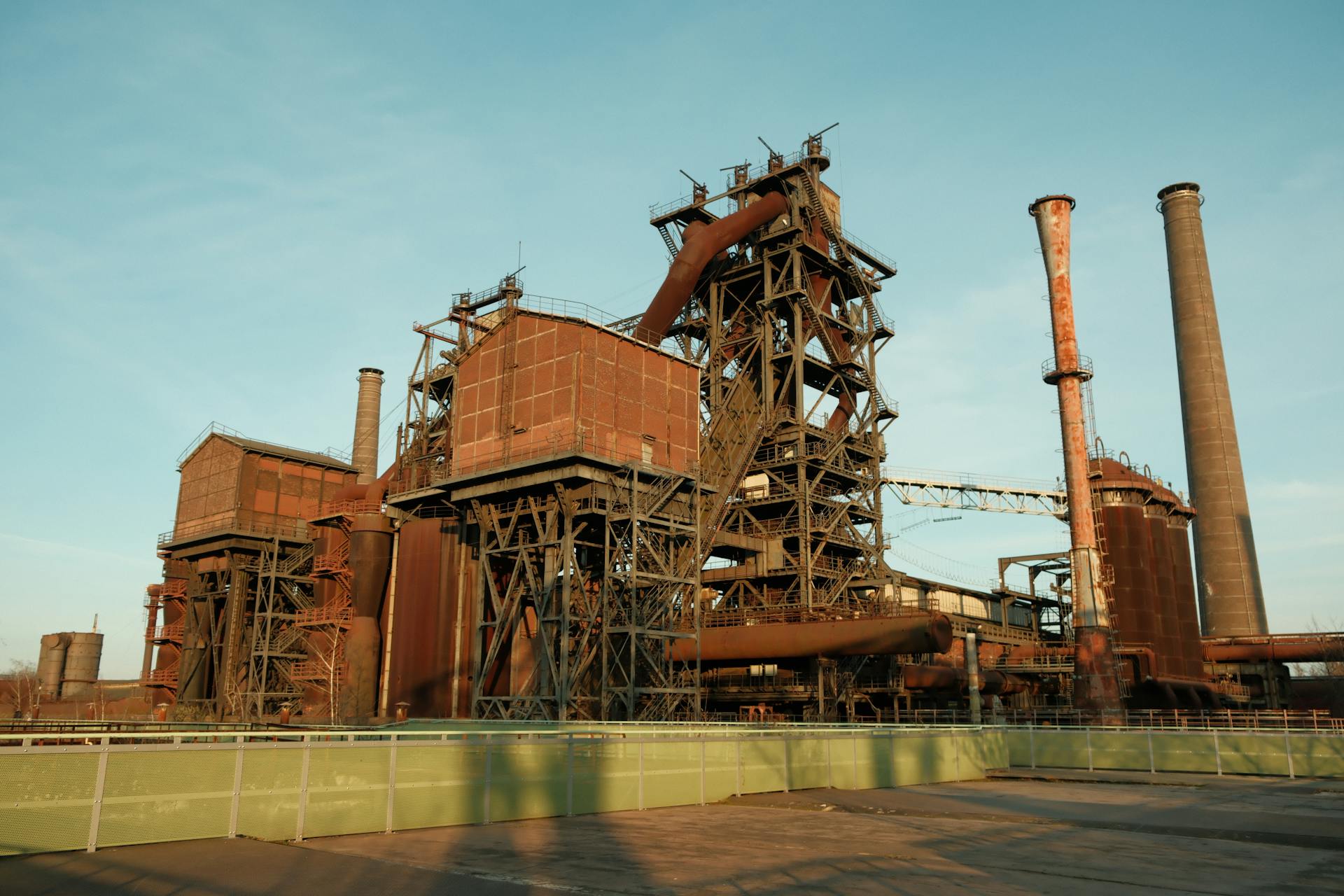 Explore the architectural structure of a historic industrial complex with striking metal frameworks and chimneys.