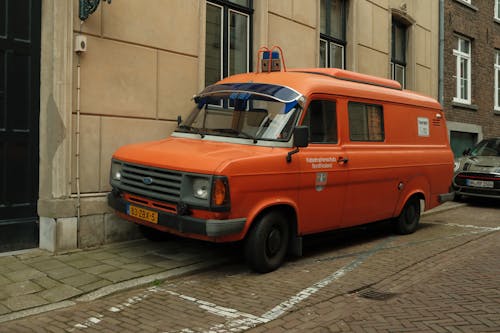 Free An orange van parked on the side of a street Stock Photo