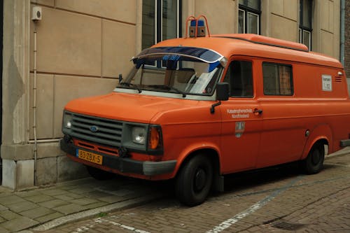 Free An orange van parked on the side of a street Stock Photo