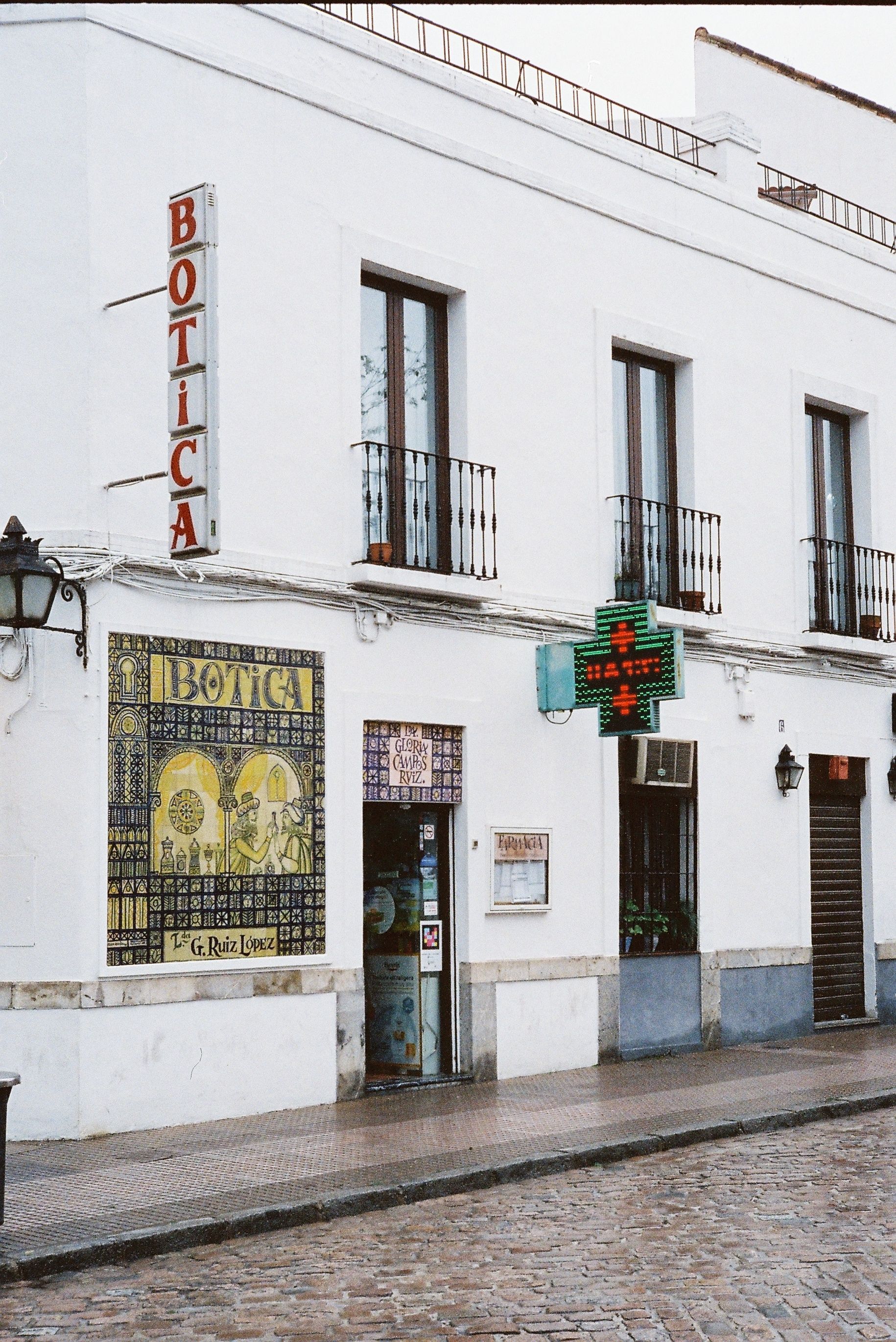 Charming view of a white pharmacy building facade with vintage signs in a Spanish town.