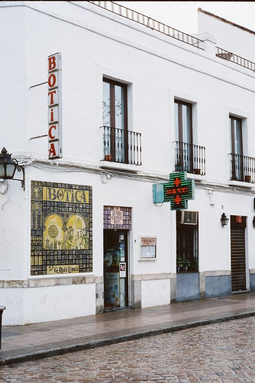Free Charming view of a white pharmacy building facade with vintage signs in a Spanish town. Stock Photo