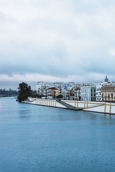 Charming view of Triana neighborhood and the Guadalquivir River in Seville, Spain. Cloudy urban landscape.