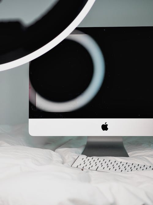 A white computer monitor sitting on top of a bed
