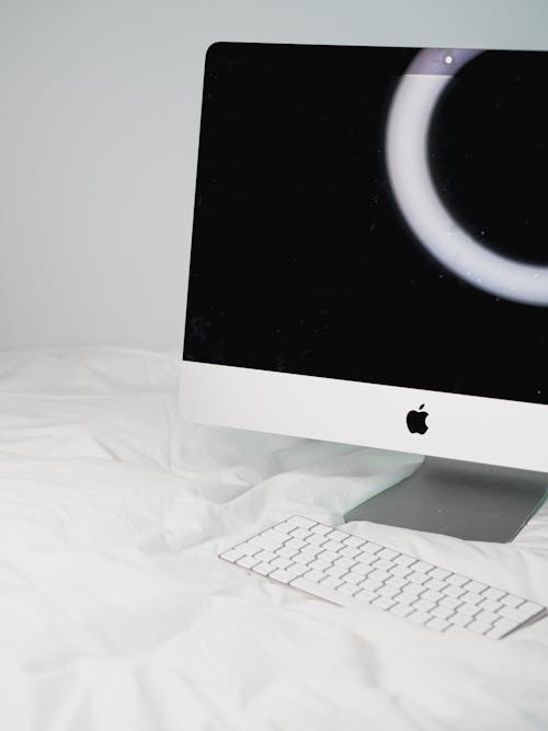 A white imac computer on a bed with a black background