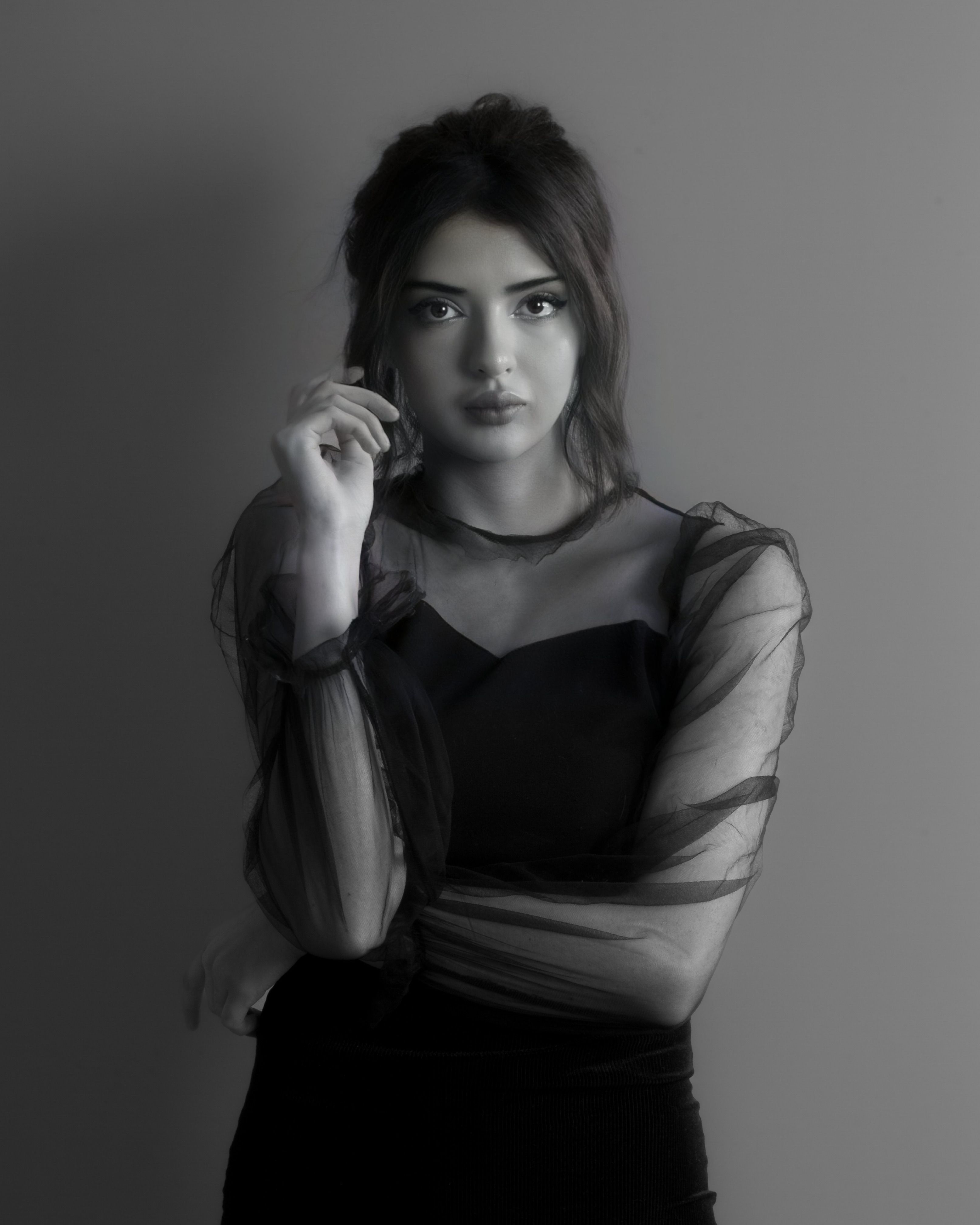 Black and white portrait of a woman in sheer black dress, exuding elegance and mystery.