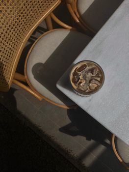 A refreshing iced coffee with milk and ice cubes on a modern cafe table.