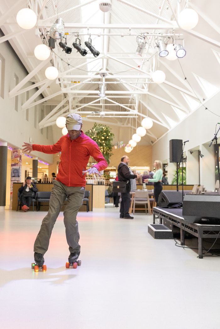 A man in a red jacket roller skating at an indoor party