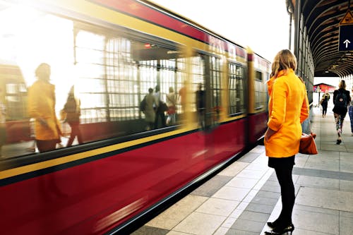 赤い電車の横に立っている女性