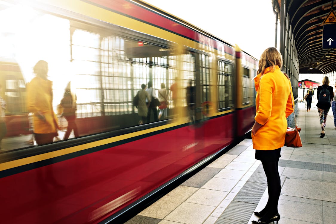 Женщина, стоящая возле красного поезда