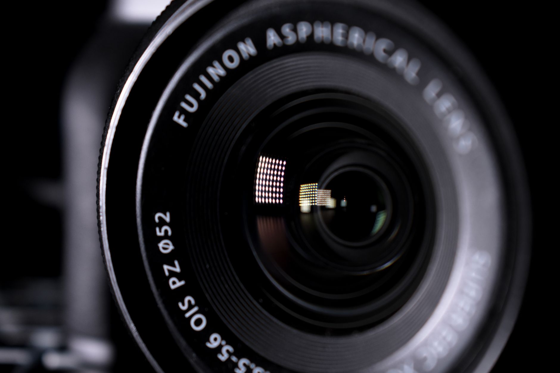 Detailed close-up image of a Fujinon aspherical camera lens with reflections.