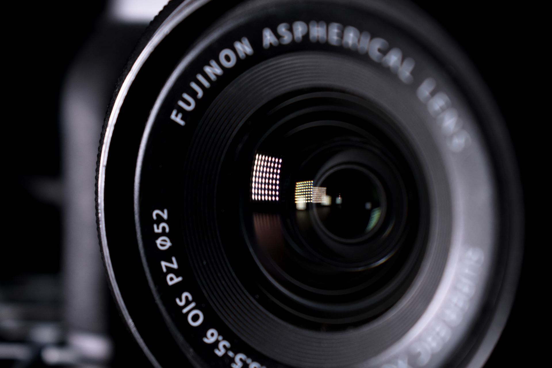 Detailed close-up image of a Fujinon aspherical camera lens with reflections.