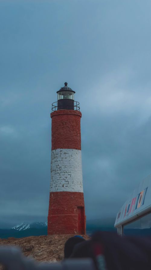 Free Lighthouse against a dramatic sky in Ushuaia, Argentina, symbolizing exploration. Stock Photo
