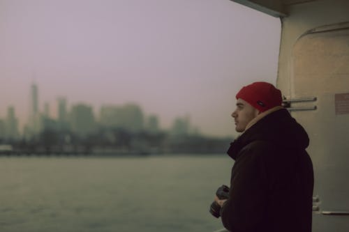 A man in a red hat looking out of a boat