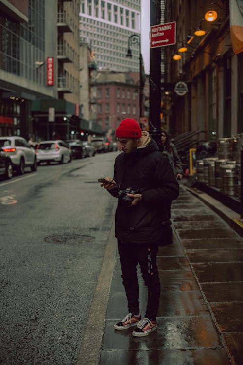 A man in a red hat is standing on a street