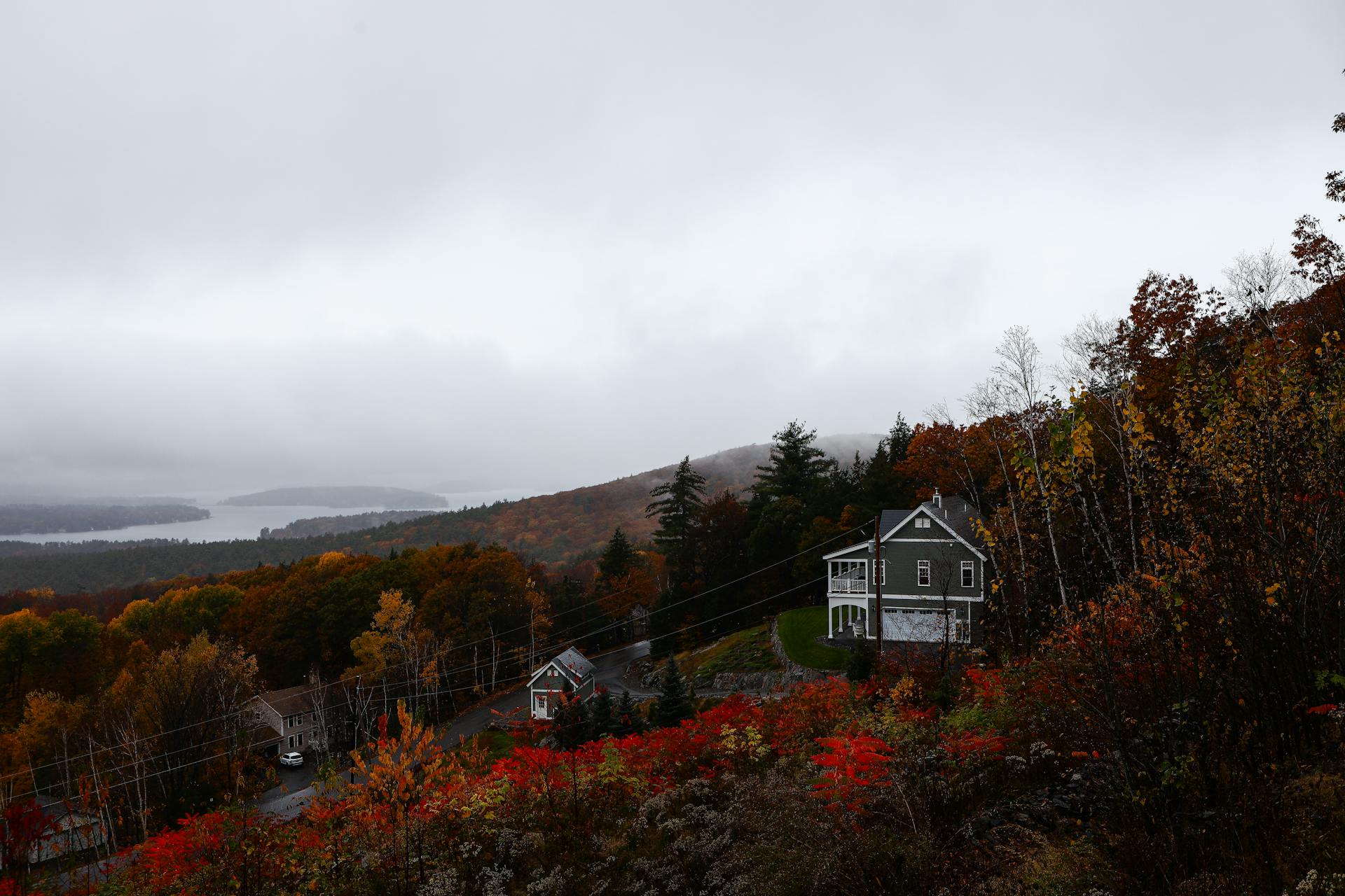 Serene autumn landscape in Gilford, NH with vibrant foliage and distant lake view.