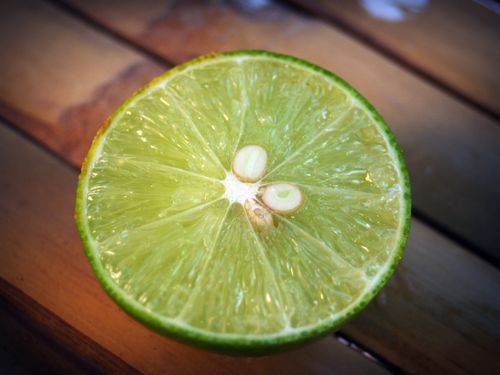 Free Fresh lime half showing juicy pulp and seeds, shot on a wooden surface. Stock Photo