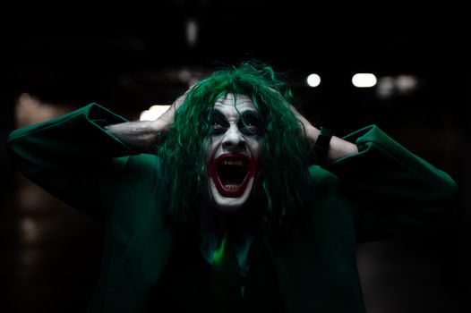 Striking portrait of a man in costume with green hair, expressing intense emotion in a dark setting.