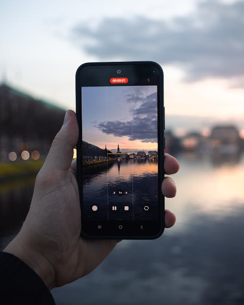 A person holding up a cell phone with a photo of a city