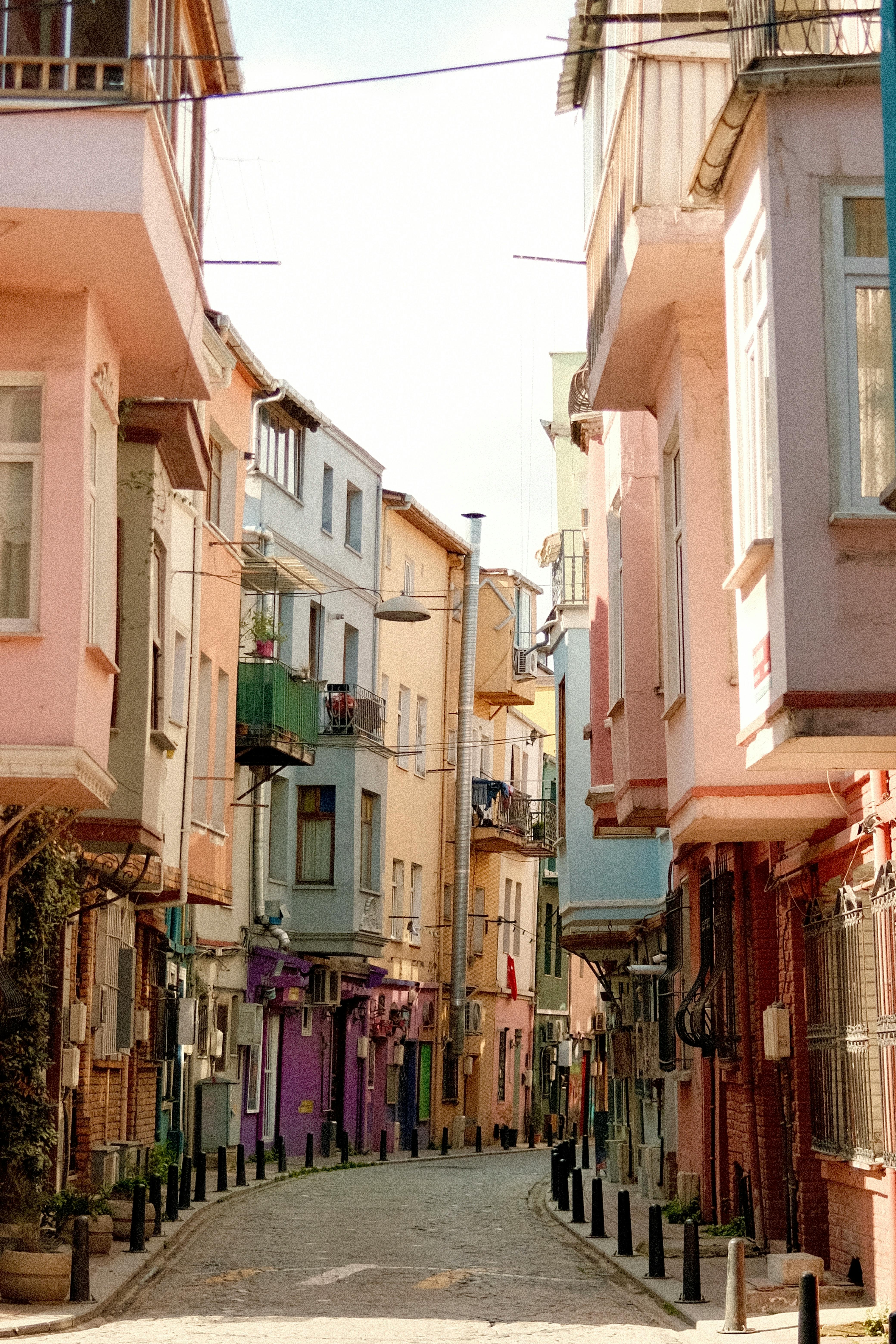 A quaint, colorful alley Iined with Mediterranean-style buildings in bright daylight.