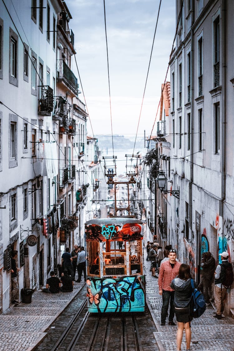 People Walking On Side Of Road Near Tram