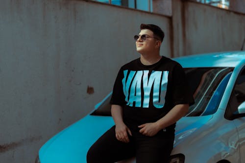 Free A man sitting on the side of a car wearing a t - shirt Stock Photo