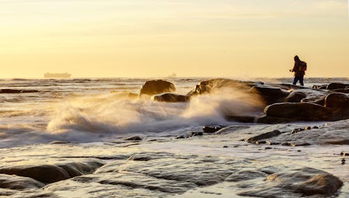 A man standing on the rocks at the ocean