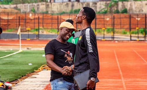 Free Two men standing on a track with one holding a ball Stock Photo